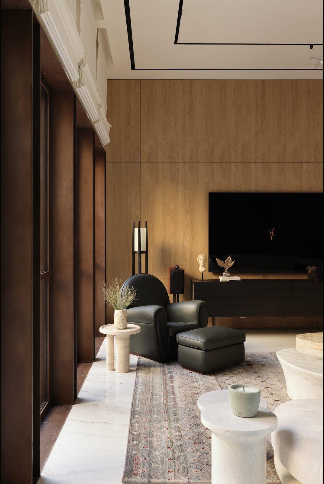 Living room with a timber-panelled media wall, a wall-mounted TV and a black armchair