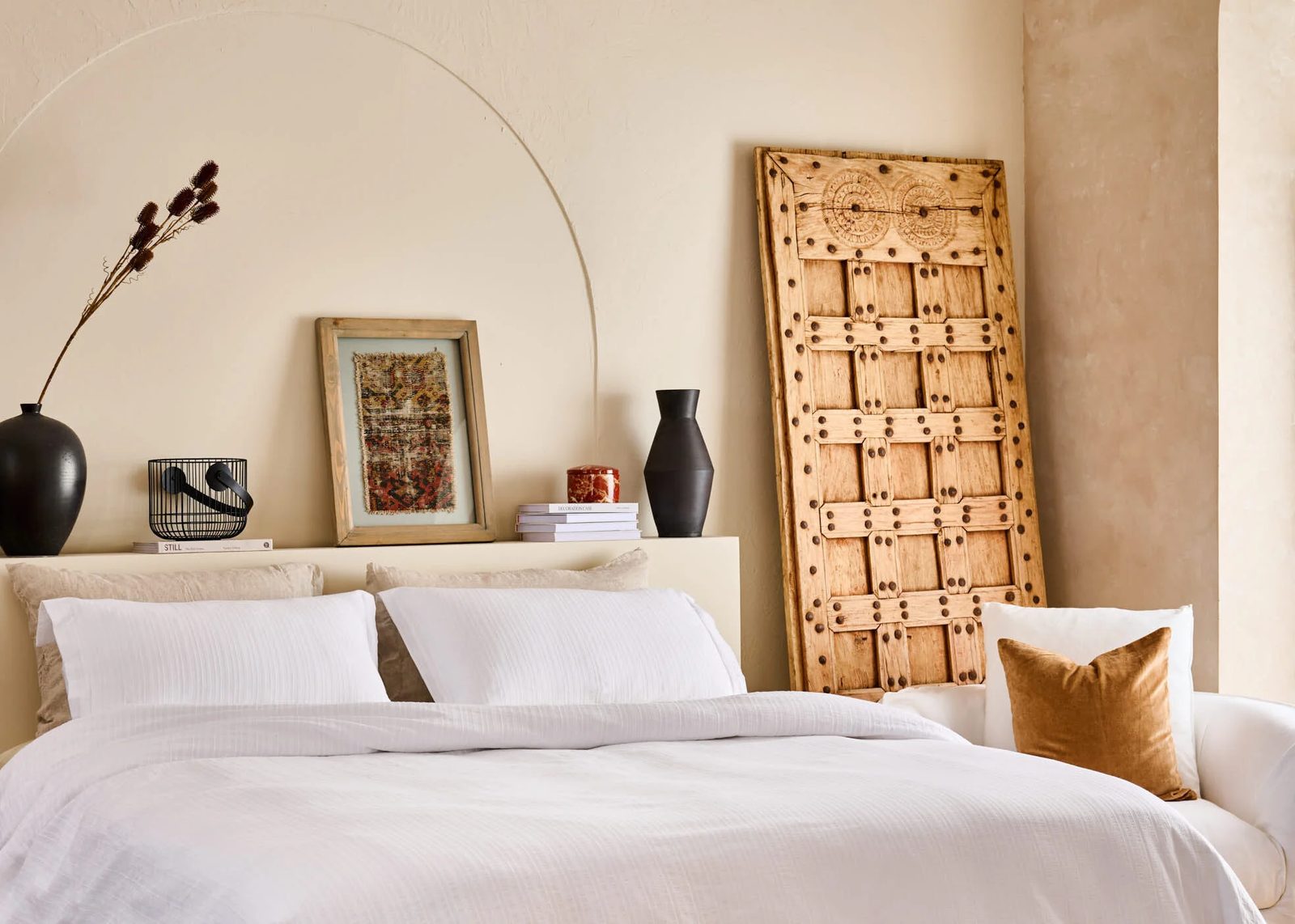 Bedroom with a cream wall, a carved wooden screen and white bedding