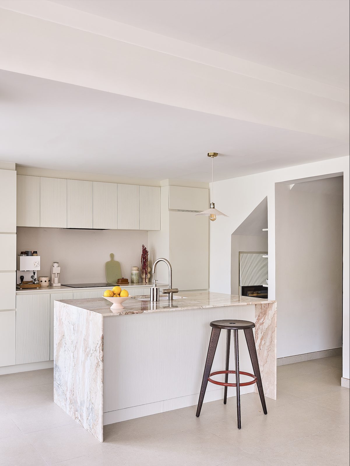 Cream kitchen with a white island and timber bar stools