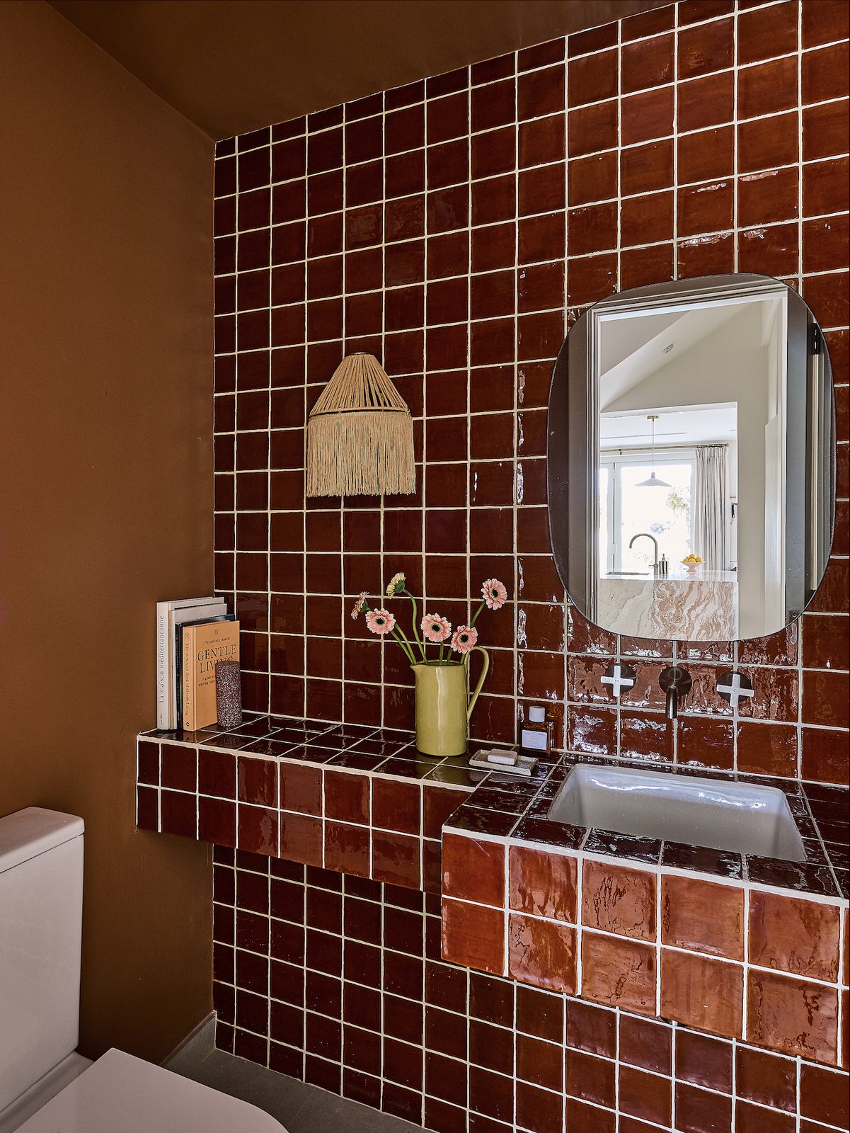 Bathroom with red tiled walls, a framed mirror and a vanity