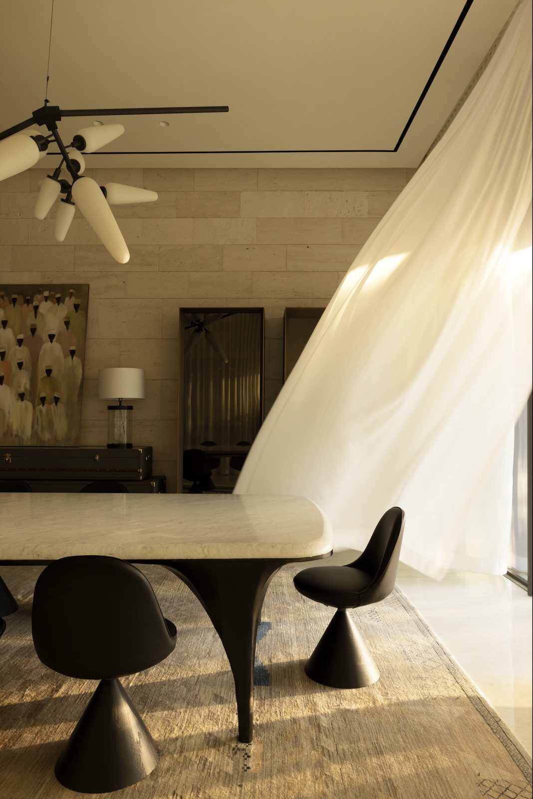 Dining area with a cream sheer drape and black tulip chairs