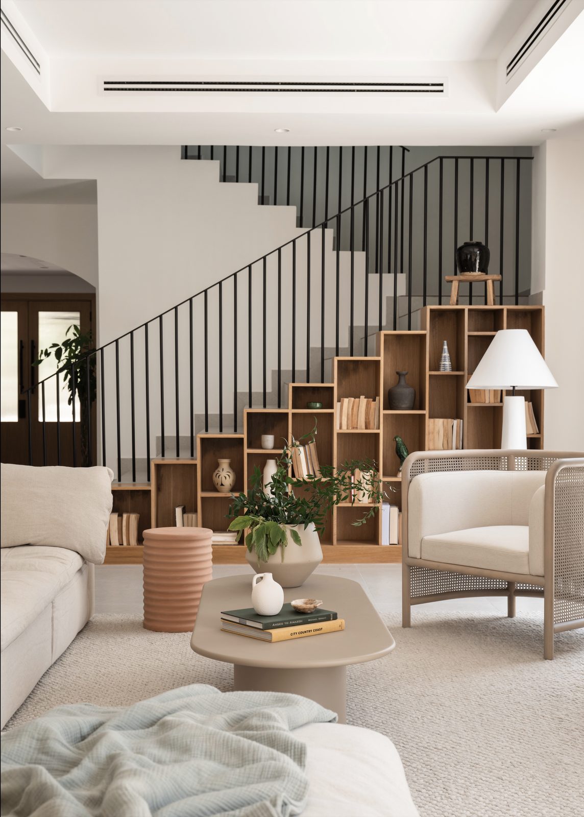 Living room with a staircase, a cream armchair and a round coffee table