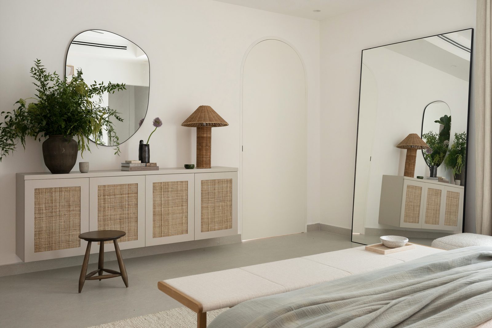 Cream vanity with a rattan-door cabinet, a table lamp and a mirror
