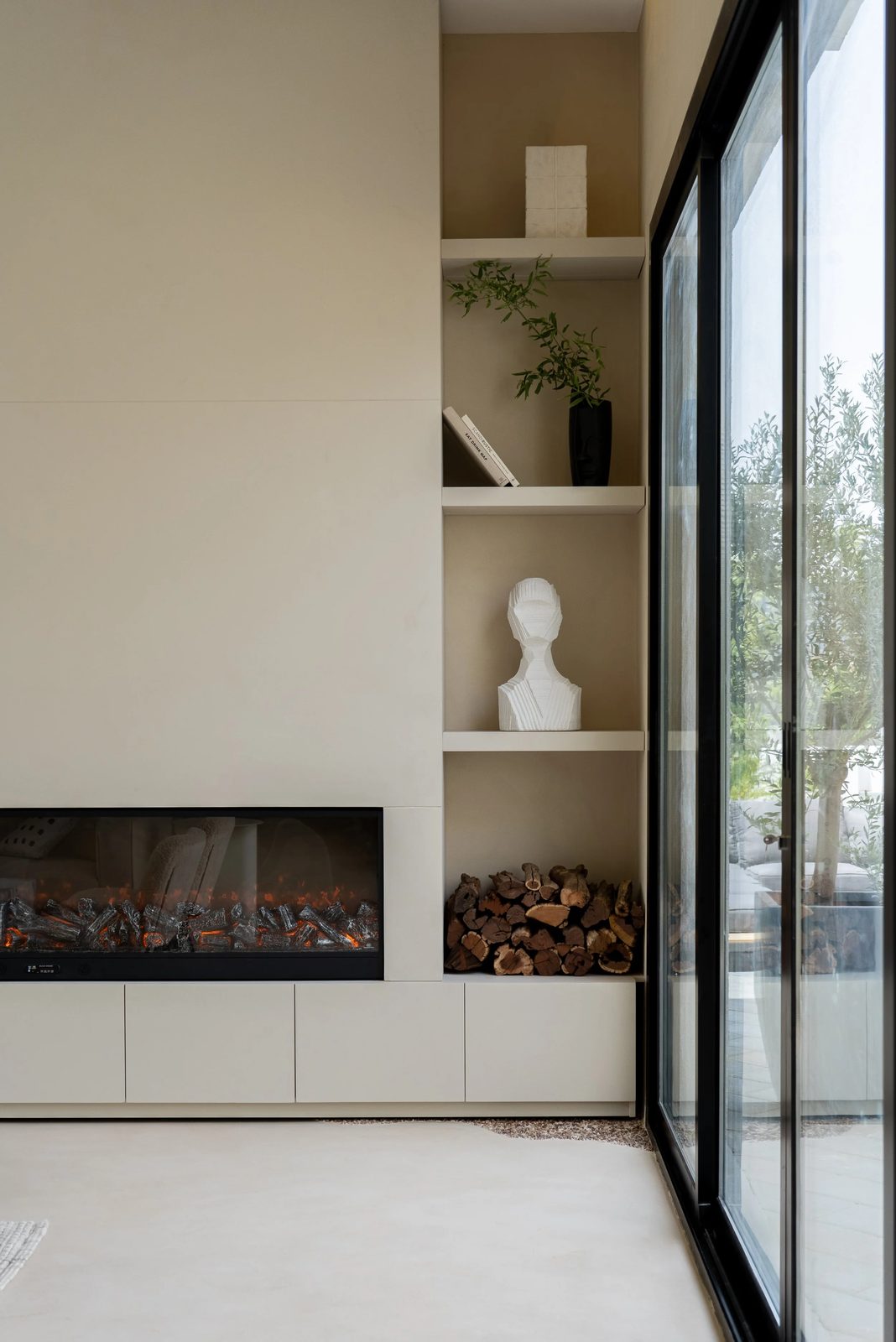 Built-in fireplace in white shelving beside glass doors